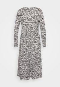 Långärmad klänning med svart bakgrund och vitt blommönster, med en figursydd ovandel och flödande kjol med rynkad midja.