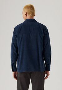 Navyblaues Langarmhemd mit Button-Down-Kragen, aus weichem Stoff, mit Knopfmanschetten und geradem Saum.