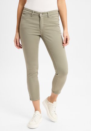 Lyse khaki skinny jeans med mid-rise midje, frontlommer og ankellang passform. Stoffet er glatt med subtile sømdetaljer.