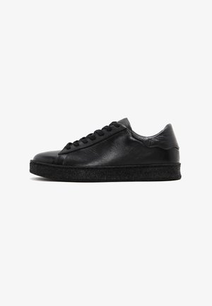 Zapatilla negra de cuero con una textura suave, punta redondeada y suela de goma negra plana. Presenta un diseño clásico de cordones y un estilo minimalista.