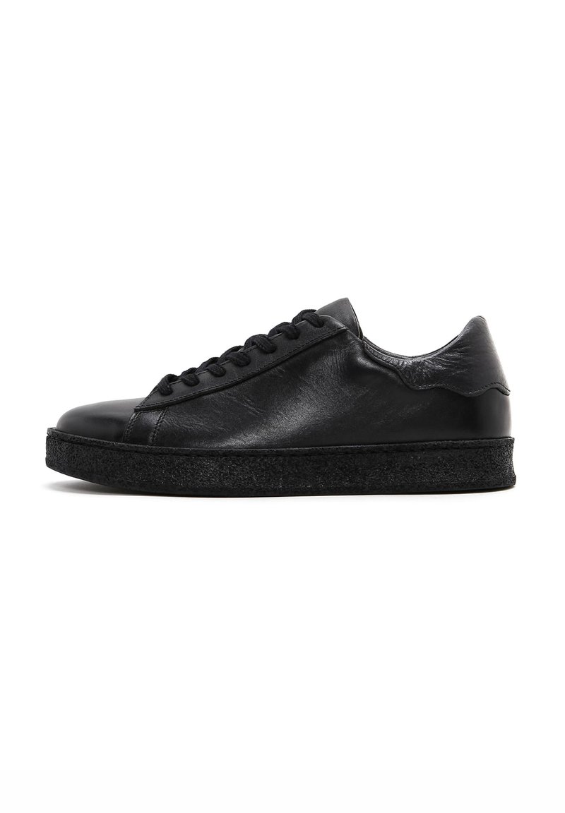 Black leather sneaker with a smooth texture, rounded toe, and flat black rubber sole. Features classic lace-up design and minimalistic style.