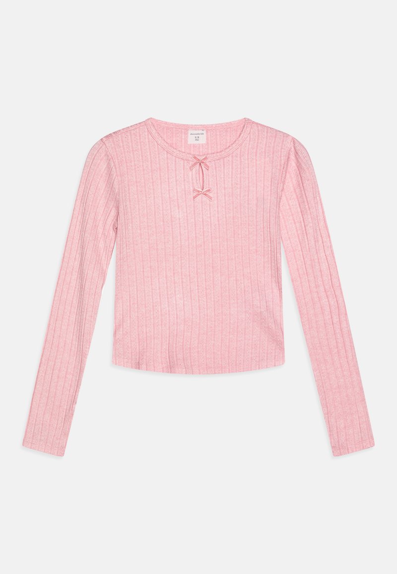 Maglietta rosa a maniche lunghe con texture a coste, scollo rotondo e due piccoli dettagli a fiocco al centro. Design cropped per un look aderente.