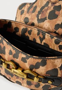Torba s uzorkom leoparda izrađena od teksturiranog materijala, s crnim akcentima i zlatnim detaljem lanca. Otvoreni interijer s crnom podstavom.