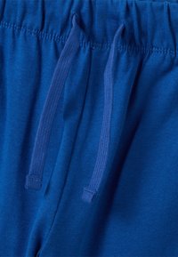 Joggers de algodón azul con cintura elástica y cordones, textura suave y acabado liso.