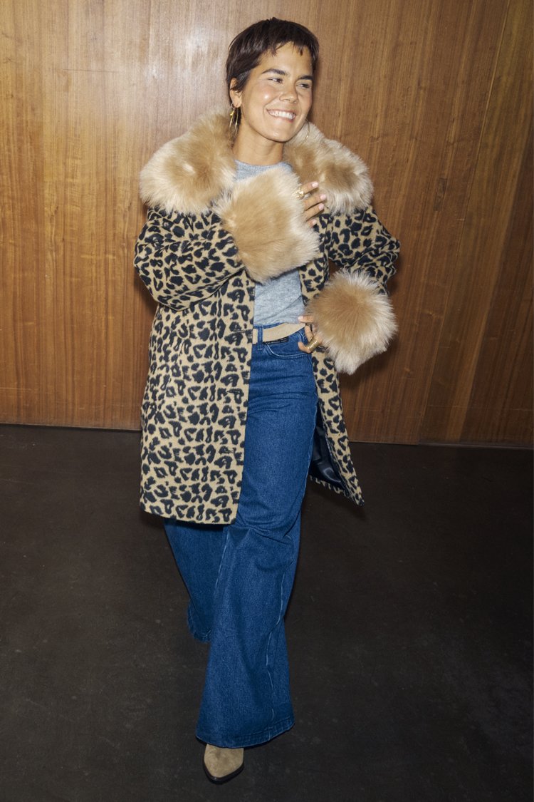 Παλτό με λεοπάρ μοτίβο και ψεύτικη γούνα στον γιακά, φορεμένο πάνω από γκρι τοπ. Το σύνολο ολοκληρώνουν ψηλόμεσα μπλε τζιν και ταμπά μποτάκια αστραγάλου.