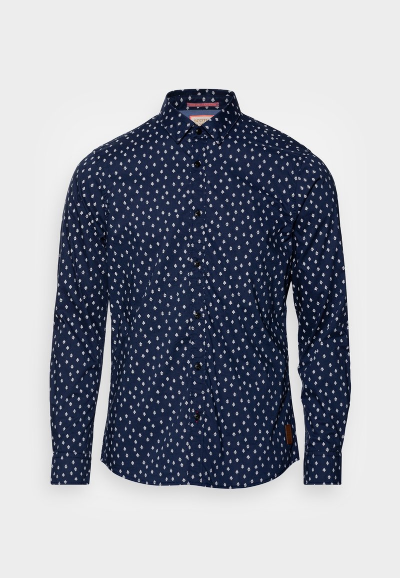 Camisa de algodón azul marino con mangas largas, que presenta un patrón de diamantes blancos, botones negros y una etiqueta de marca en el dobladillo.