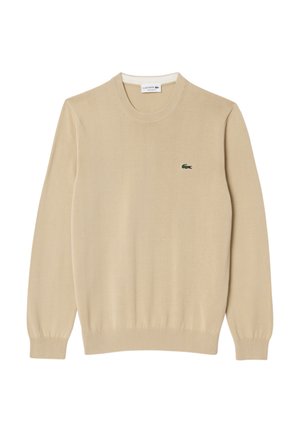 Beige striktrøje med lange ærmer, rund halsudskæring og ribbede manchetter. Har et lille grønt Lacoste-logo på brystet.