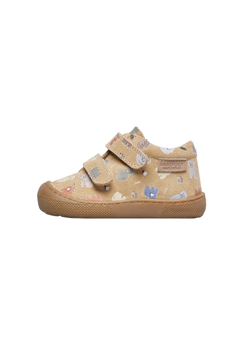 Chaussures pour enfants avec un extérieur en suedine beige arborant un motif d'animaux ludique. Deux bandes velcro maintiennent la chaussure. Semelle en caoutchouc texturée.