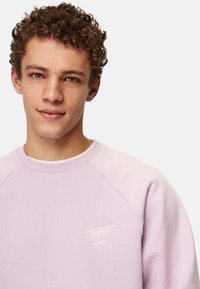 Valkoinen vaaleanpunainen huppari raglan-hihoilla, tekstuuripinnalla ja pienellä valkoisella "Honest Rules" -logolla vasemmassa rintapielessä.