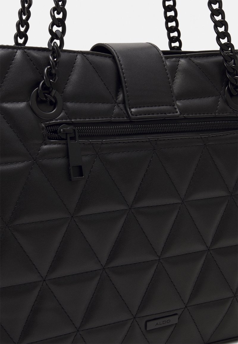 Sac à main noir matelassé avec coutures triangulaires, poignées en chaîne, poche avant zippée et petite étiquette de marque.