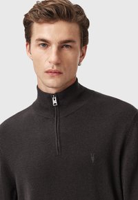 Ciemnoszara sweter na zamek z teksturowanej tkaniny. Posiada wysoki kołnierz oraz małe logo na lewej piersi. Czysty, nowoczesny design.