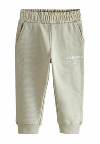 Svetlé béžové detské jogger nohavice s elastickým pásom, bočnými vreckami, rebrovanými manžetami a bielym logom "ALLSAINTS" na ľavom stehne.