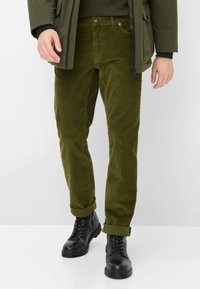 Olivengroene corduroy broek met een rechte pasvorm, voorzien van een knoopsluiting en opgerolde manchetten, gecombineerd met zwarte hoge combatlaarzen.