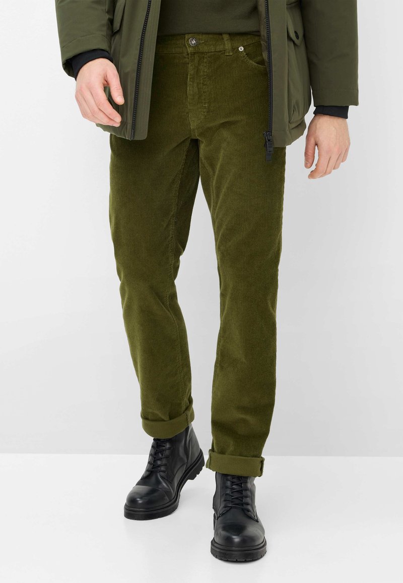 Olivengroene corduroy broek met een rechte pasvorm, voorzien van een knoopsluiting en opgerolde manchetten, gecombineerd met zwarte hoge combatlaarzen.