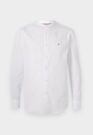 Cămașă albă cu mâneci lungi și nasturi, guler mandarin și mic logo brodat pe pieptul stâng.