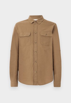 Chemise marron à manches longues avec boutons, col et deux poches poitrine devant, présentée sur un fond gris clair uni.