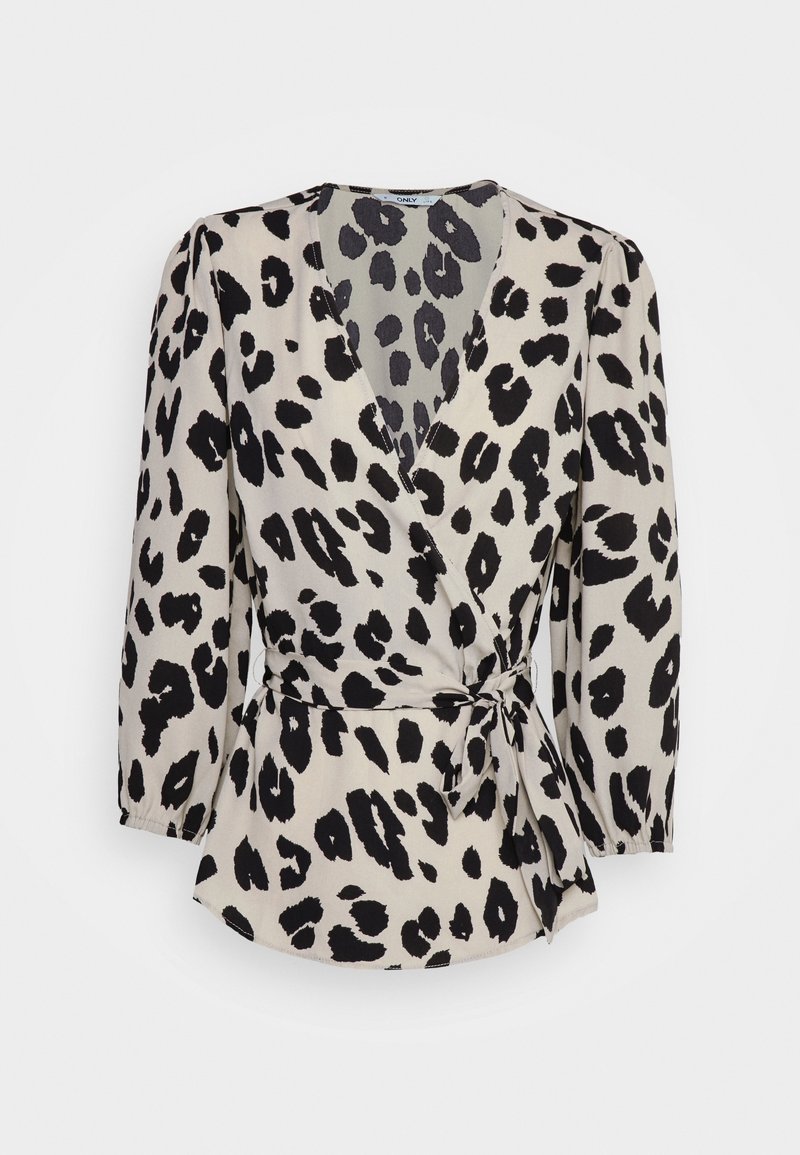 Blouse portefeuille beige avec des taches léopard noires irrégulières, manches longues bouffantes, et un lien sur le côté à la taille.