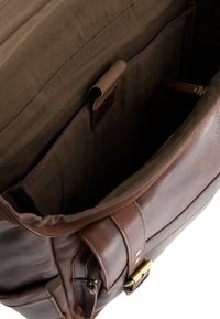 Brun lædertaske med et rummeligt beige indre. Har en lynlåslukning, indvendig lomme og et robust strop med messinghardware.