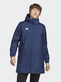Tenká parka v námořnické modré barvě s kapucí, elastickými manžetami a bočními kapsami. Na horní části levé hrudi je logo Adidas.