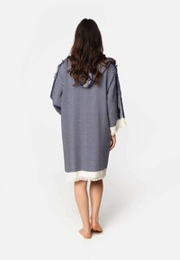 Marineblauwe en witte herringbone-patroon poncho met gefranjerde zoom, losse mouwen en een ontspannen pasvorm, ontworpen voor comfort en warmte.