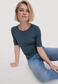 Donkerblauwe korte mouwen t-shirt met een ronde hals, gemaakt van soepele, rekbare stof, gecombineerd met lichtblauwe spijkerbroek.