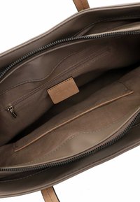 Grand sac fourre-tout marron en cuir lisse, avec fermeture éclair et deux poches intérieures ; doublé d'un tissu doux et texturé.