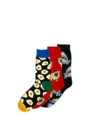 Trzy kolorowe skarpetki: jedna z jajkami sadzonymi na czarnym tle i żółtym palcem u nogi, druga czerwona z mopslami i zielonym piętą, trzecia czarna z rekinami i rozbryzgami wody.