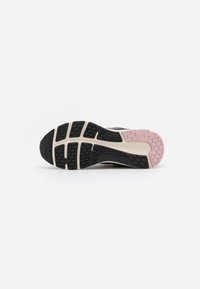 Suela de una zapatilla de correr con una banda de rodadura de goma negra, beige y rosa que presenta patrones hexagonales y rectangulares.