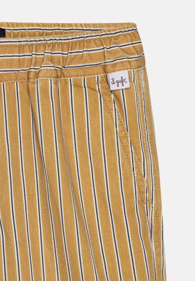 Stripete bomullsbukser i sennepsgul, med hvite og marineblå vertikale striper, elastisk livlinje og en liten merkelapp på lommen.