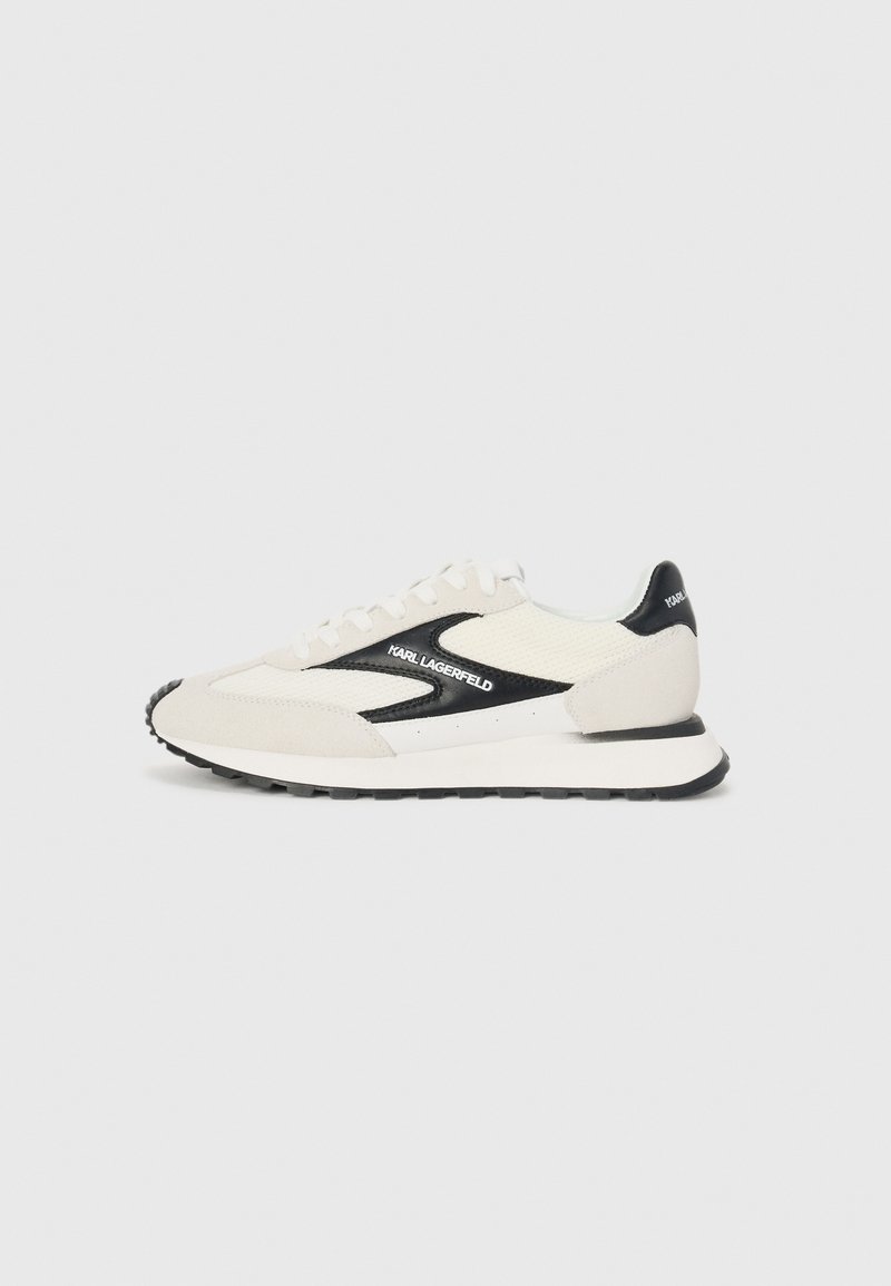 Hvit og grå sneaker med svarte detaljer, med et mesh-overdel og semsket skinn, snøring, og gummisåle.