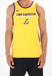 Débardeur Nike jaune avec bordure violette, affichant le texte "LOS ANGELES" et un logo des Lakers à l'avant. Design léger et sportif.