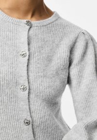 Pelēks adīts kardigans ar ribotu tekstūru, apaļu kakla izgriezumu un sudraba dekoratīvajiem pogām gar priekšpusi.