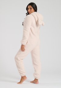 Lichtroze fleece onesie met een capuchon, textuur oppervlak, elastische manchetten en enkels, met een speelse afgeronde accent op de capuchon.