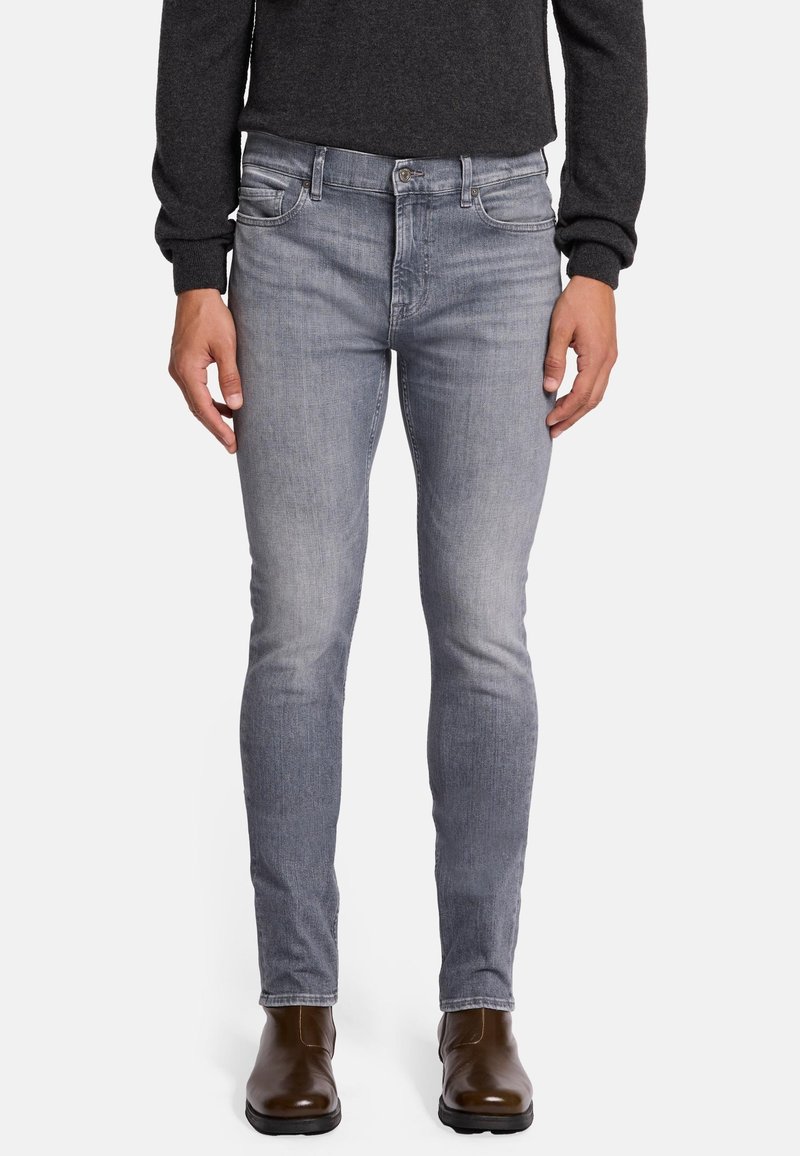 Jeans in denim skinny-fit grigio chiaro, con una leggera sfumatura, design a cinque tasche e zip frontale. Abbinati a stivaletti alla caviglia marroni.
