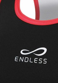 Canottiera sportiva nera con colletto rosso, caratterizzata da un logo bianco "ENDLESS" e un simbolo dell'infinito. Realizzata in materiale liscio ed elastico.