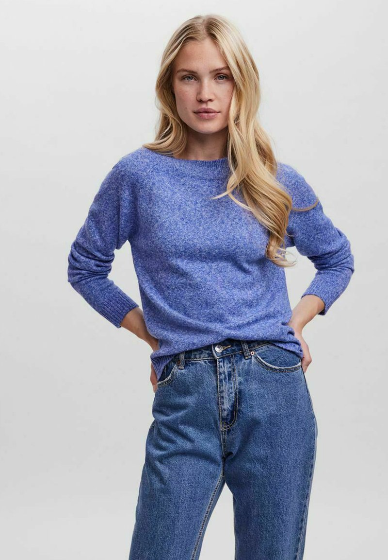 Blue knitted sweater with a round neckline, long sleeves, and a textured finish, paired with high-waisted blue jeans.