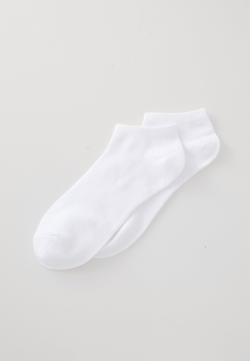 Une paire de chaussettes blanches unies posées à plat sur une surface claire, sans motifs ni logos visibles.