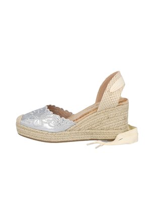 Sandalia de cuña espadrille con punta de encaje floral, plataforma de yute tejido y correa para atar al tobillo en tonos beige y plata.