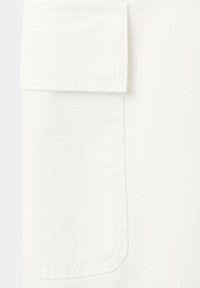 Poche en tissu blanc avec rabat, présentant des coutures discrètes et un bord inférieur arrondi sur un fond blanc assorti.