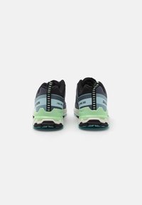 Black and blue athletic shoes with a green sole. Features textured mesh, contrasting accents, and a patterned heel tab for support.