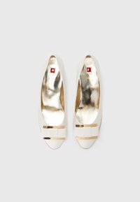 White pump shoes with a smooth finish, featuring gold hardware accents and a square red emblem on the insole. Rounded toe design.