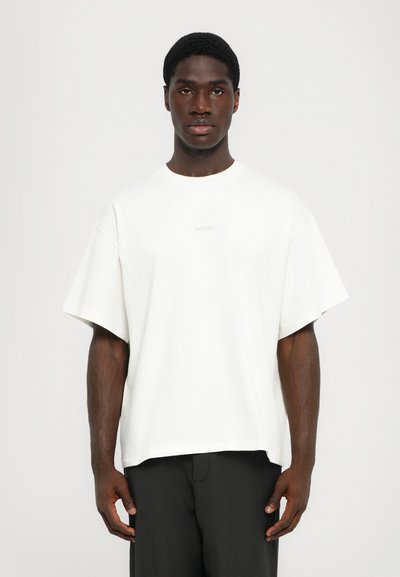 Λευκό oversized t-shirt με κοντά μανίκια, διαθέτει στρογγυλή λαιμόκοψη και διακριτό λογότυπο "WON" στο κέντρο. Λείο ύφασμα με άνετη εφαρμογή.