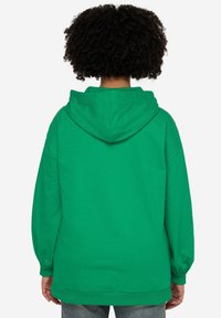 Felpa verde con cappuccio, caratterizzata da una texture morbida, maniche lunghe e una vestibilità comoda. Cuciture visibili e polsini a coste.