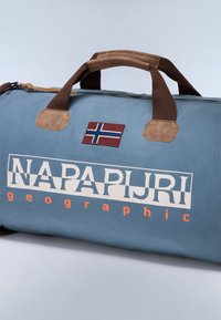 Borsa a tracolla blu con manici marroni, caratterizzata da una toppa con la bandiera norvegese e una grande scritta bianca "NAPAPIJRI" con accenti arancioni sul lato.