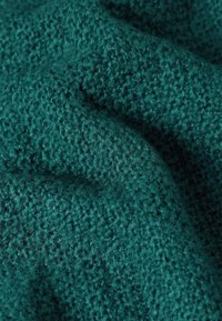 Textured fabric in dark teal color, featuring a knitted pattern with a soft, fuzzy surface and subtle variations in weave.