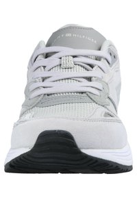 Scarpa sportiva grigio chiaro con una combinazione di materiali scamosciati e a rete, punta rotonda, lacci e suola in gomma nera con dettagli bianchi.