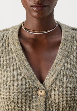 Green textured cardigan with a V-neck and a single light button closure. Smooth metallic choker necklace layered over the collar.