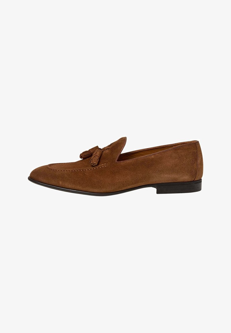 Mocassin homme en daim marron avec pompons, talon bas noir, bout arrondi et détails cousus sur la tige.