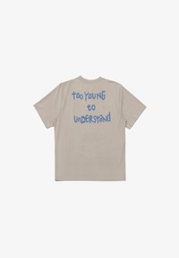 Beige bomulls t-shirt med korta ärmar. Bakdelen har blå text som läser "FÖR UNG för att FÖRSTÅ" i ett lekfullt typsnitt.