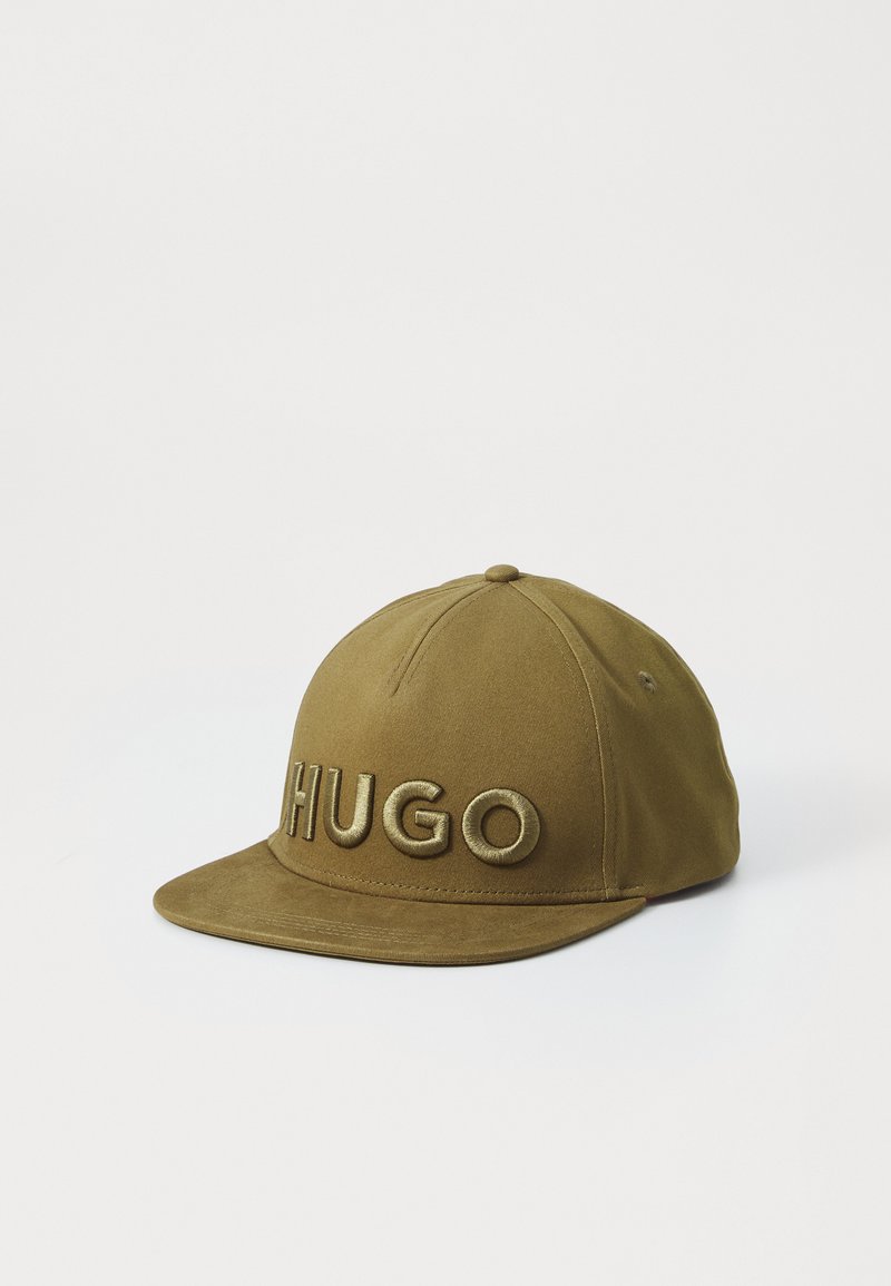 Khaki színű baseball sapka hímzett "HUGO" logóval, sötétebb árnyalatban. Lapos karima, testhezálló kialakítás és texturált anyag jellemzi.